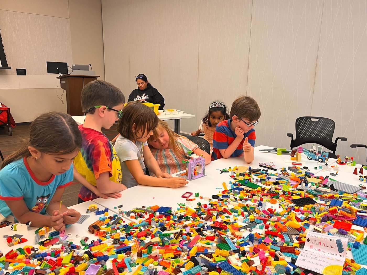 Students working together at a long table covered in building bricks during a Design Your World session