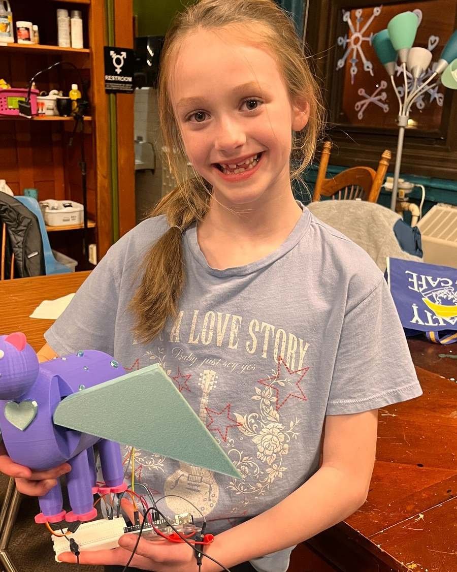 A Design Your World student holding the purple robotic pet she designed, printed and wired herself
