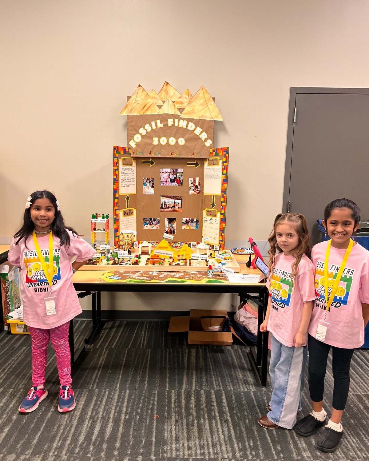 Design Your World students standing with a project display they built together