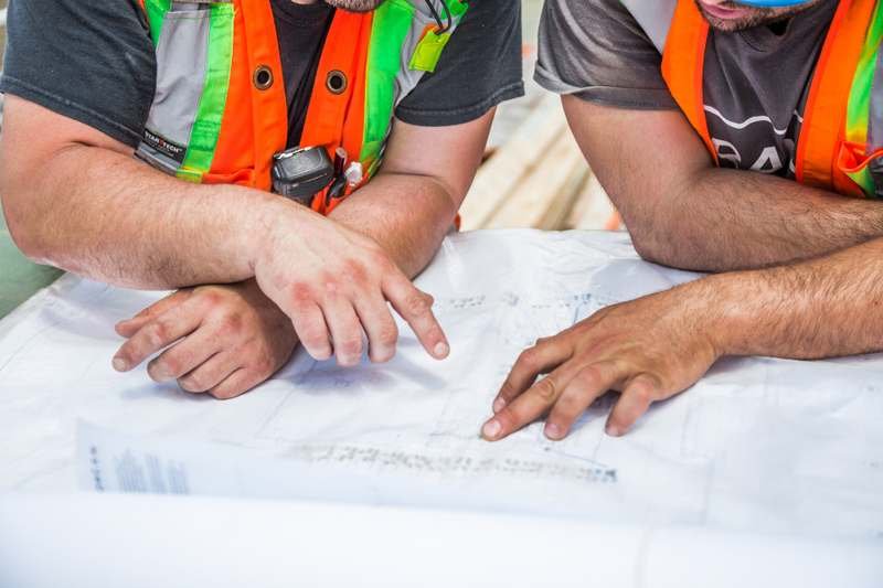 Hands reviewing a technical drawing on a workbench