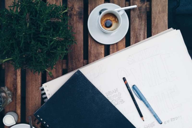 An open notebook with a product design sketched in pencil beside a pen
